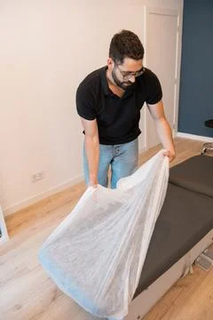 Physiotherapist preparing massage table for clean patient treatment 库存照片