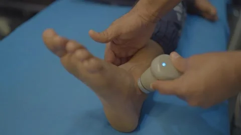 Physiotherapist puting gels with machine on patient ankle pain relief Stock Footage 312256257
