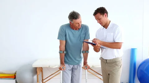 Physiotherapist talking to patient on crutches Stock Footage 34669523