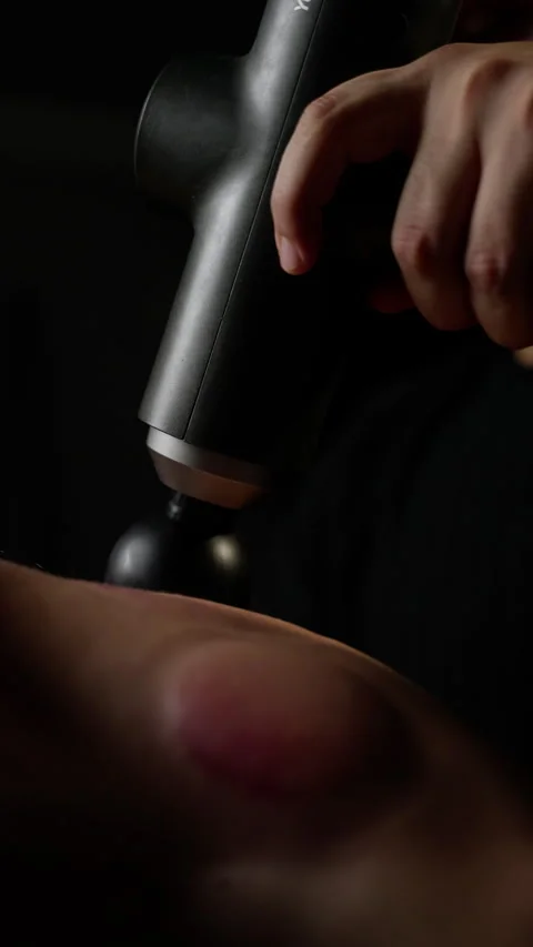 Physiotherapist treating muscle tension, using percussion massage device on Stock-Footage 300366845