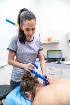 Physiotherapist using instrument on patient's back muscles Stock Photos