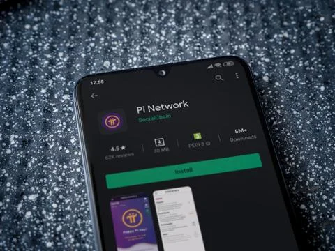 Pi Network app play store page on the display of a black mobile smartphone on Stock Photos