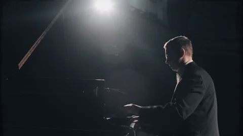 Pianist in black suit masterfully playing the grand piano on big stage  Stock Footage 123544665