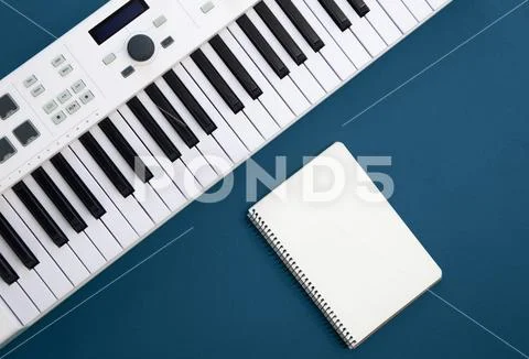 Phím đàn piano và sổ ghi chú trống trên nền xanhPhím đàn piano và sổ ghi chú trống trên nền xanh  