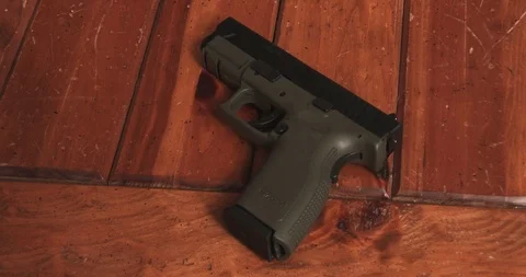 Pick Up 9mm Semi Automatic Handgun off a Wooden Table Stock Footage 85653569