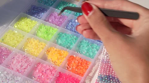 Pick a colorful gem and carefully place it onto object for bedazzling Stock Footage 343441101