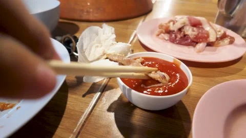 Pick up some pork and dip it in the sauce. 動画素材 290503093