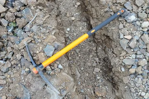 Pickaxe hoe lying on the ground. hand-held percussion tool designed for worki Foto stock