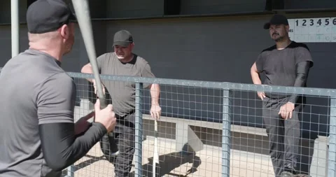 Picking up bat, Diverse male baseball teammates gathering in dugout warming up, 動画素材 344104216