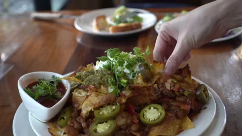 Picking cheesy nacho chips with salsa and minced meat dipping Mexican appet.. Stock Footage 302519833