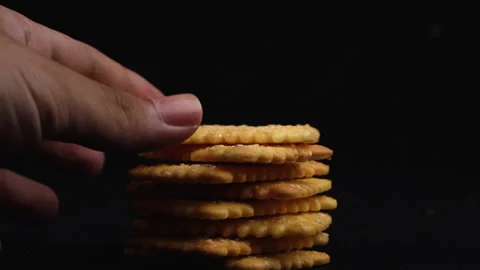 Picking a crackers , medium close up , black background Видео 135778364