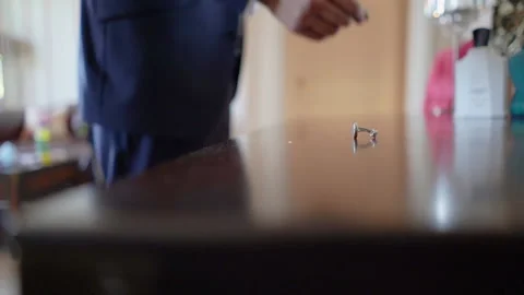 Picking up cuff links from the table by a man front of the dressing table. Stock Footage 193586753