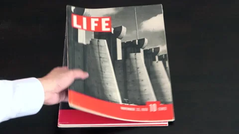 Picking Up First Issue of Life Magazines From A Pile Stock Footage 219160744