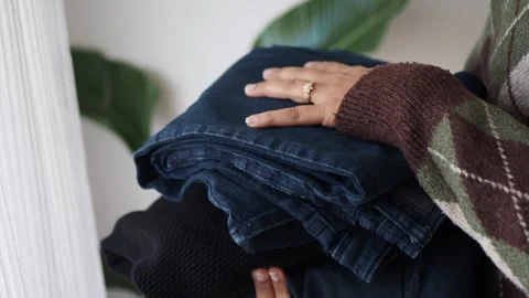 Picking up folded clothes and organizing them in a home Stock Footage 332529163