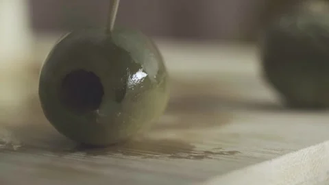 Picking green pitted olive with toothpick macro close up slow motion food Stock Footage 271060844
