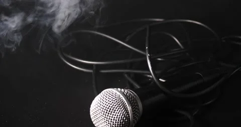 Picking up microphone then dropping it isolated on black close-up smoke Stock Footage 204062803