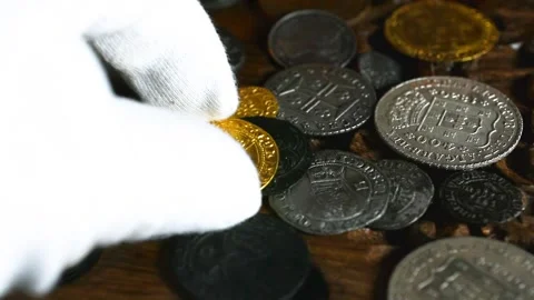 Picking up an old gold coin Stock Footage 333610859