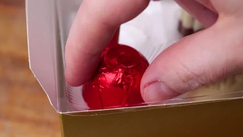 Picking red chocolate candy from box in slow motion Stock Footage 306412524