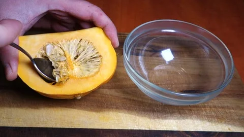 Picking seeds from the pulp of the pumpkin with a spoon Stock Footage 168651270