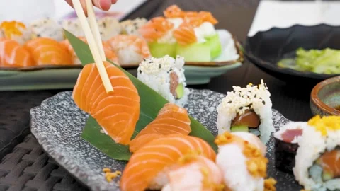 Picking a slice of raw salmon and dipping it in soy sauce Stock Footage 272702958