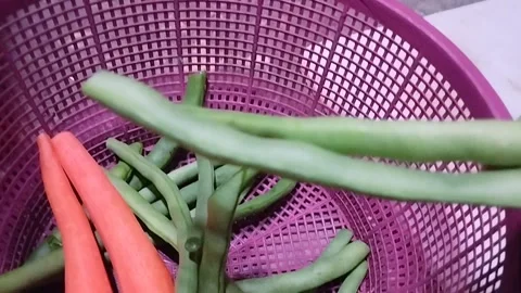 Picking Two Green Beans from a Pink Woven Tray to Place on a Cutting Board Stock Footage 321785934