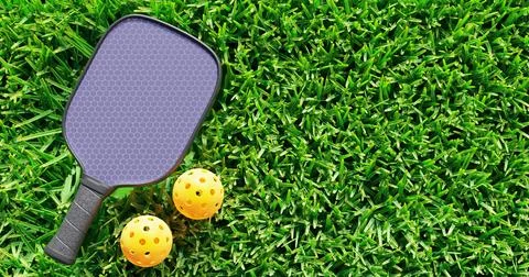 Pickleball. One racket two balls on green grass. Stock Photos