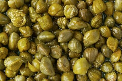 Pickled capers as a background. Marinated buds of caper bush. Stock Photos