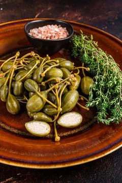 Pickled Capers berries in a rustic plate. Dark background. Top view Stock Photos