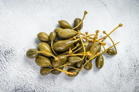 Pickled capers on a kitchen table. White background. Top view Stock Photos