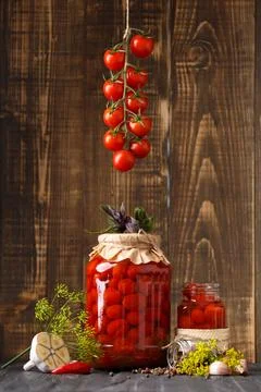 Pickled cherry tomatoes in jars and spices on a wooden background Stock Photos
