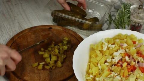 Pickled cucumbers are cut into small pieces with kitchen knife on cutting board Stock Footage 234848953