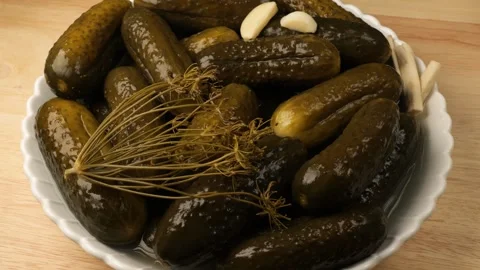 Pickled cucumbers with dill and garlic rotating on a wooden table Stock Footage 344915490