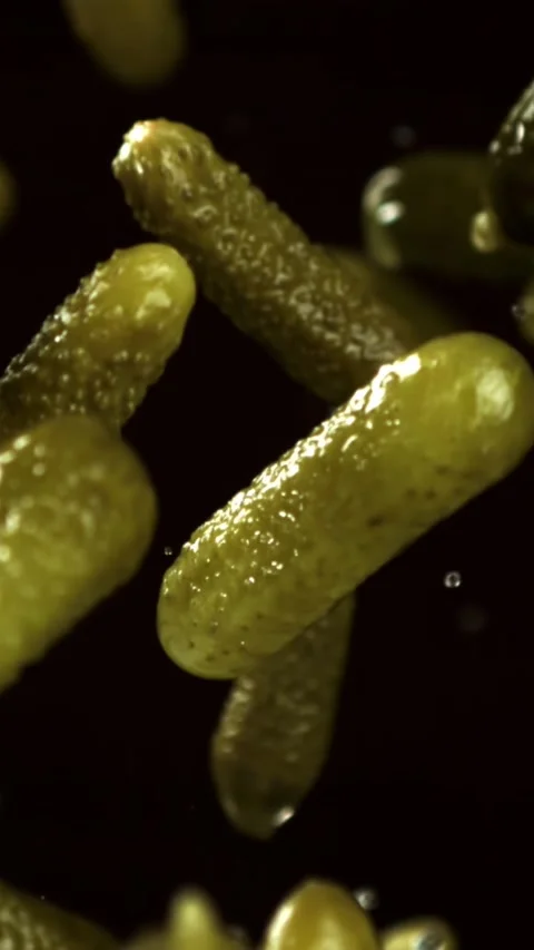 Pickled cucumbers fly and fall on a black background. Filmed on a high-speed Stock Footage 335373923