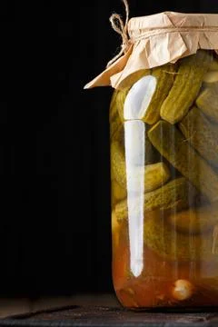 Pickled cucumbers in a jar on a dark background close-up. Stock Photos
