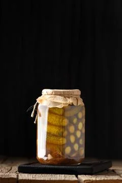Pickled cucumbers in a jar on a dark background with place for text close-up. Stock Photos