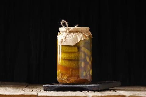 Pickled cucumbers in a jar on a dark background close-up, copy space. Stock Photos