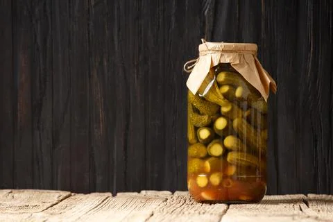 Pickled cucumbers in a jar on a dark background, copy space Stock Photos