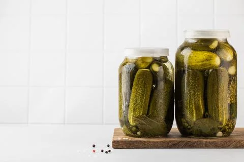 Pickled cucumbers in jars on a white background. Canning vegetables. Copy space. Stock Photos