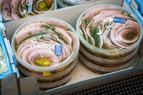 Pickled herring fillets with herbs in plastic containers on a supermarket shelf. Stock Photos