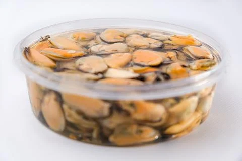 Pickled mussels in plastic jars. Assorted canned seafood on the counter Stock Photos