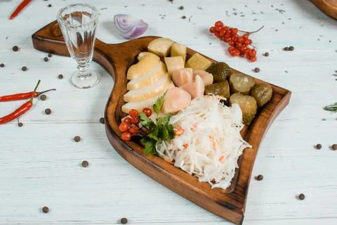 Pickled vegetables on a plate on white table with spices on background tradit Фото