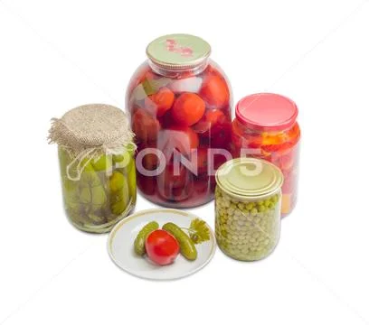 Pickled vegetables on saucer and in glass jars Stock Photos