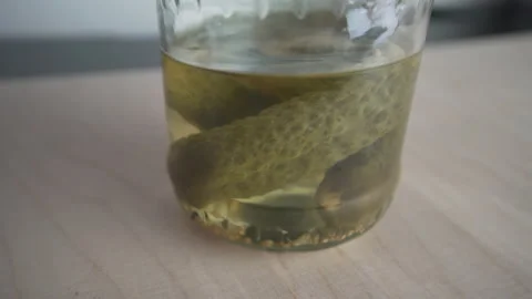Pickles in jar, pickled cucumber shaking laid on wooden table Stock Footage 158531051