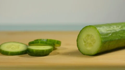 Picks up a chopped piece of cucumber from the kitchen table and puts Stock Footage 128917747