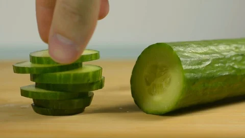 Picks up a chopped piece of cucumber from the kitchen table Stock Footage 128917754
