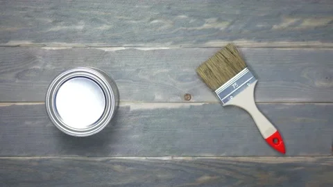 Picks up a paint can and a paint brush from the table Stock Footage 143420360