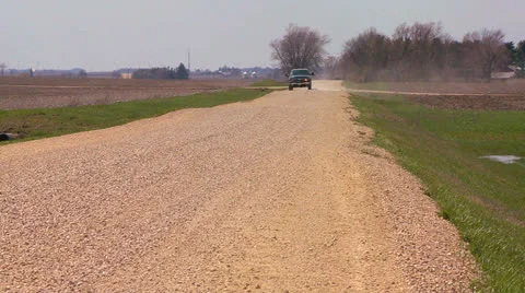 A pickup truck drives on a dirt road through Midwest farmland. Stock Footage