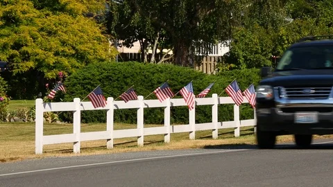 Pickup truck passing American flags in small town USA Stock Footage