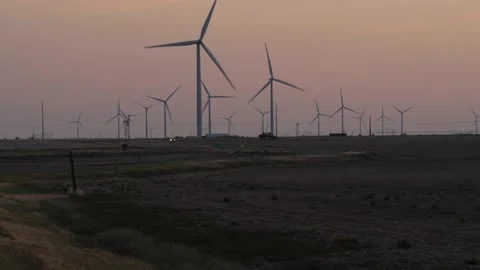 A pickup truck passing through a wind farm in the morning light Stock Footage 134401839