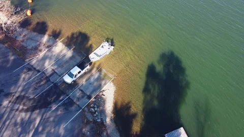 Pickup truck pulling boat and trailer out of the water at the shore of a lake Stock Footage